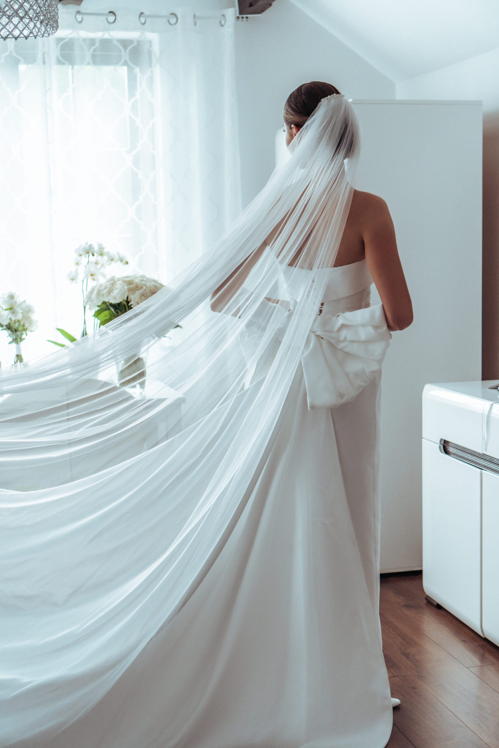 Panna młoda tyłem z długim, ciągnącym się welonem. Fotografia ślubna detale sukni Gorzów Wielkopolski, Strzelce Krajeńskie.