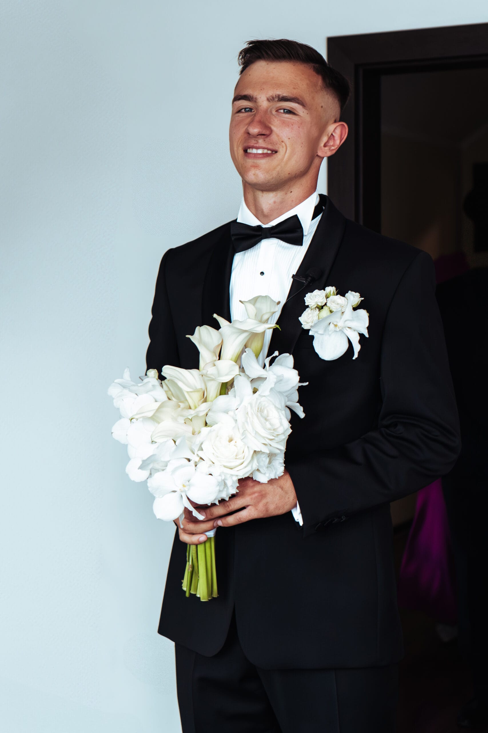 Uśmiechnięty Pan Młody z bukietem kwiatów ułamek sekundy przed pierwszym spotkaniem z Panną Młodą. Fotografia ślubna Gorzów Wielkopolski, Skwierzyna.