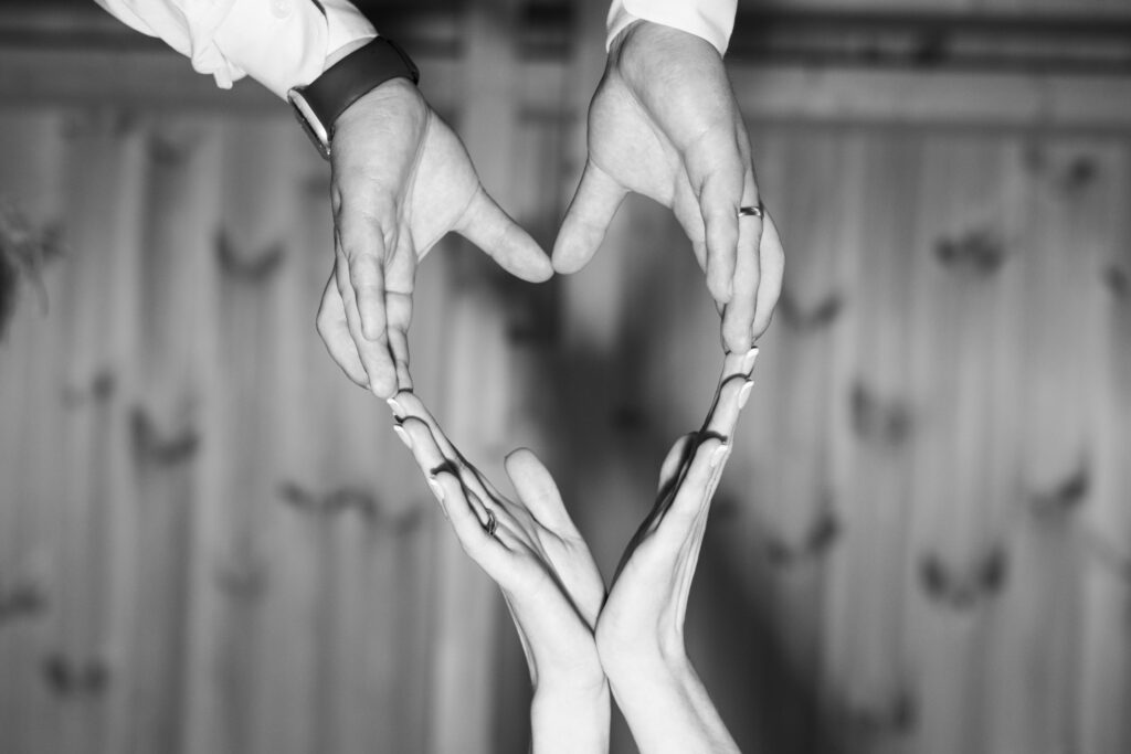 Artystyczne czarno-białe zdjęcie dłoni Pary Młodej ułożonych w serce, widok od dołu. Fotografia ślubna Gorzów Wielkopolski, Lubniewice.