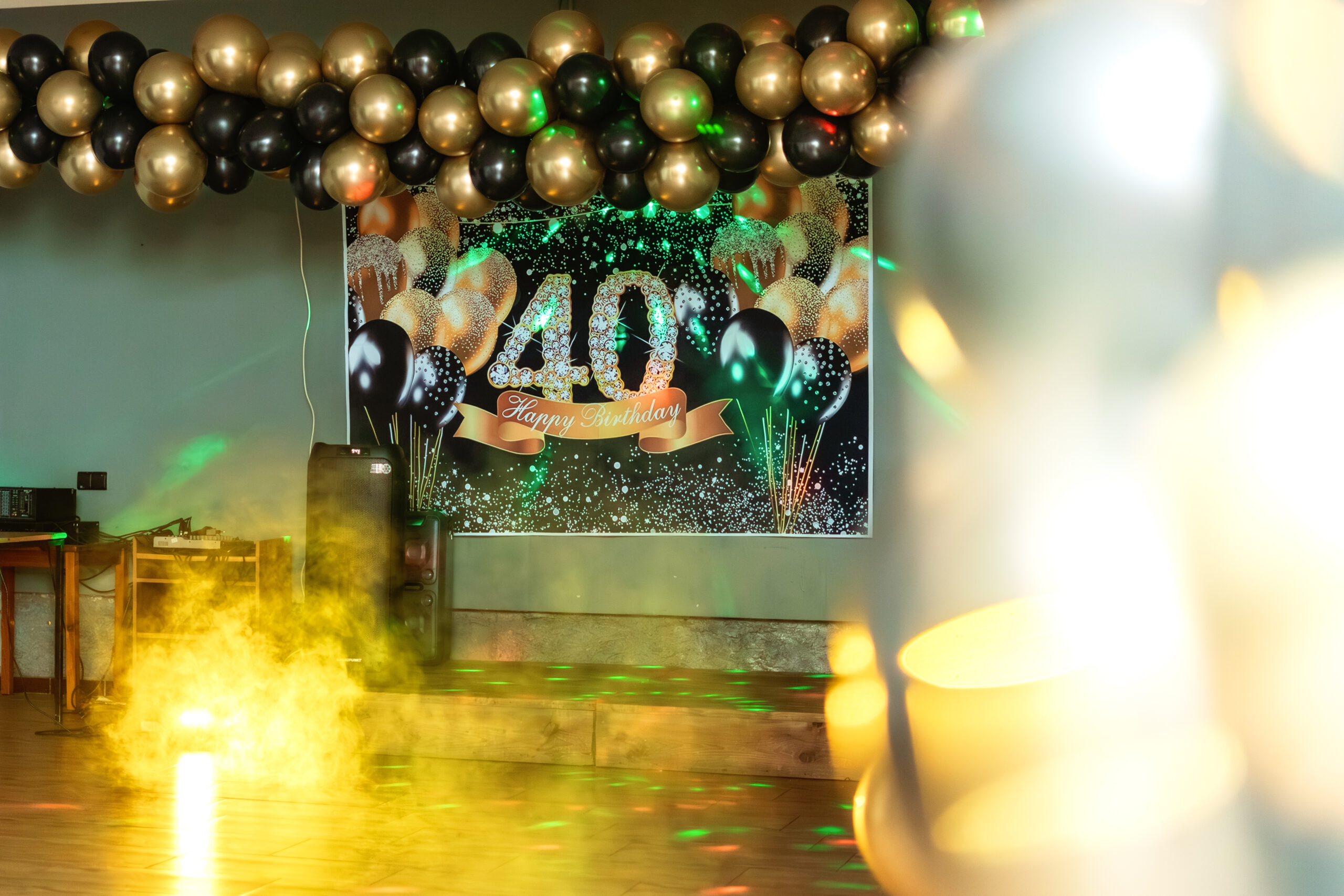 Złoty baner z napisem 40 Happy Birthday na tle czarnych i złotych balonów dekoracyjnych.