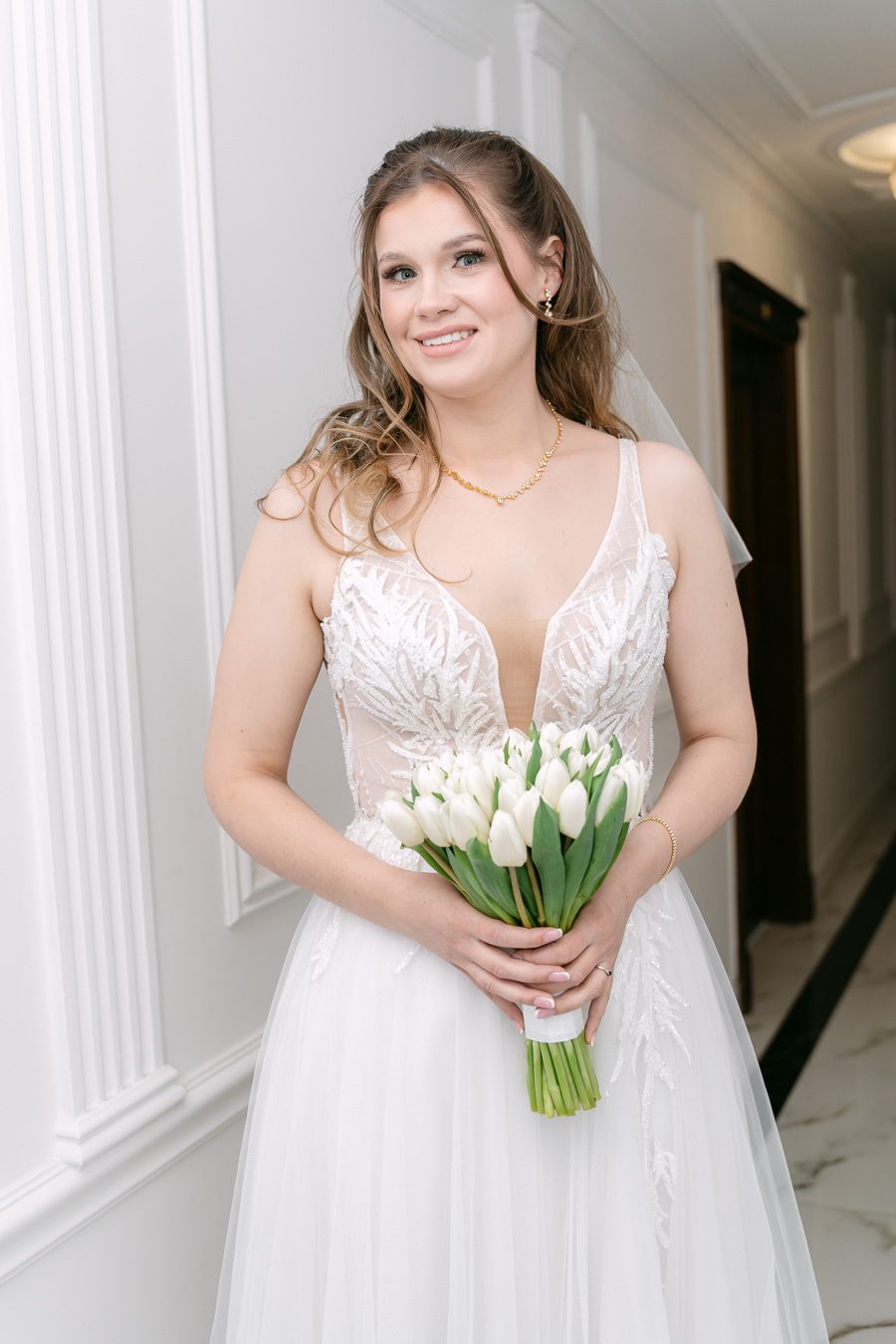 Portret panny młodej w koronkowej sukni ślubnej trzymającej bukiet białych tulipanów, profesjonalna fotografia ślubna Gorzów Wielkopolski.