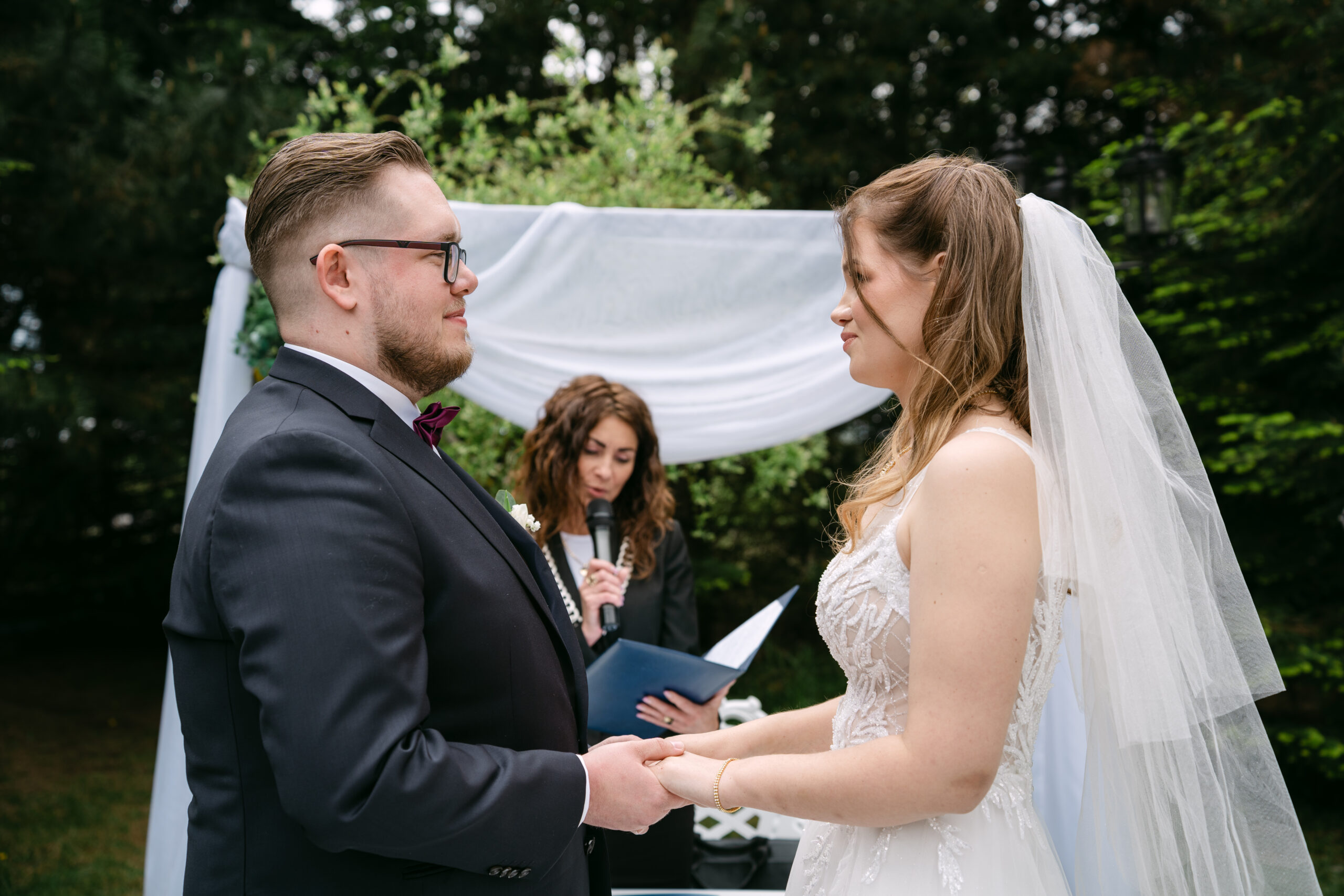Bliski kadr na czuły gest Moniki trzymającej Sebastiana za policzek tuż po ceremonii ślubnej. Naturalne, pełne miłości zdjęcia ślubne wykonane w plenerze przy Dworku Kurowskim.