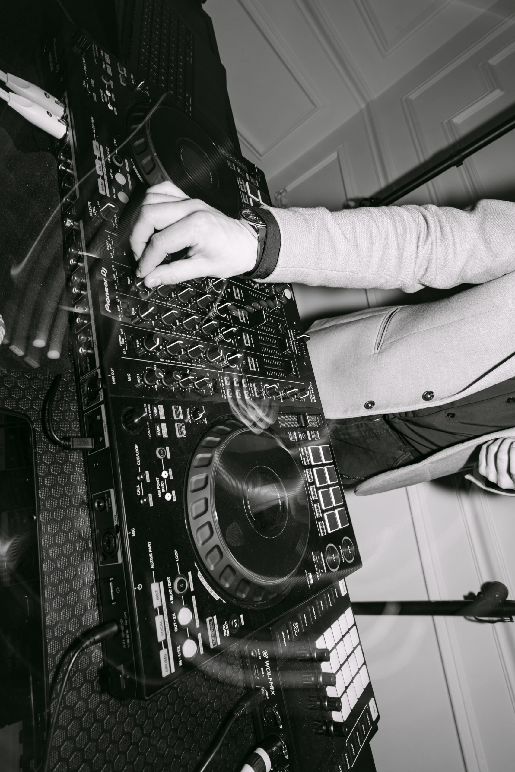 Czarno-biały, bliski kadr na konsolę DJ-a Pioneer podczas miksowania muzyki. Dynamiczny reportaż z zabawy weselnej Moniki i Sebastiana w Dworku Kurowskim.